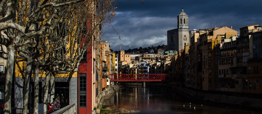 Girona river and church with dark sky. Captured by Richard Hadley, wedding and portrait photographer.